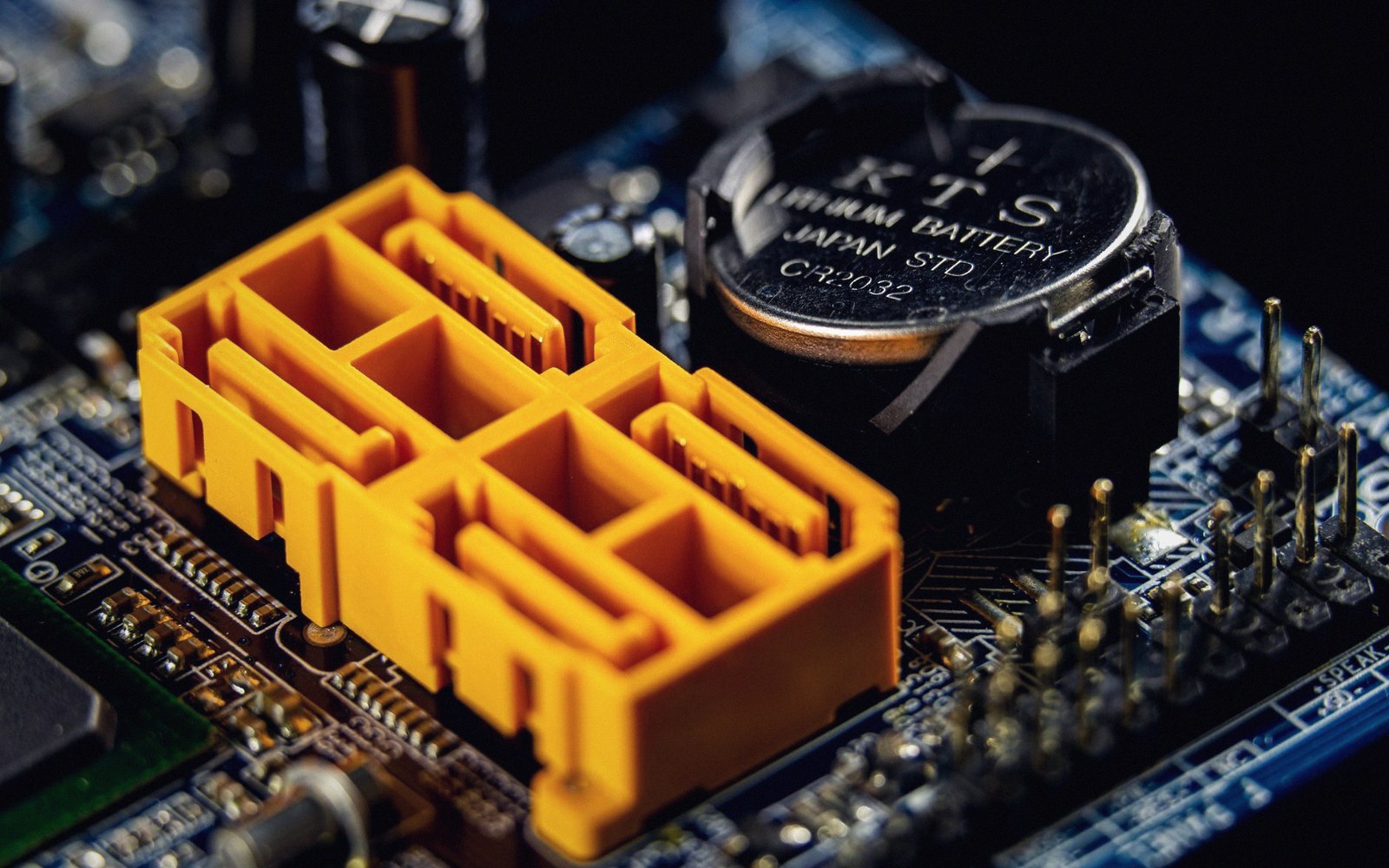 Close-up of a motherboard showing an orange SATA connector beside a CR2032 lithium battery