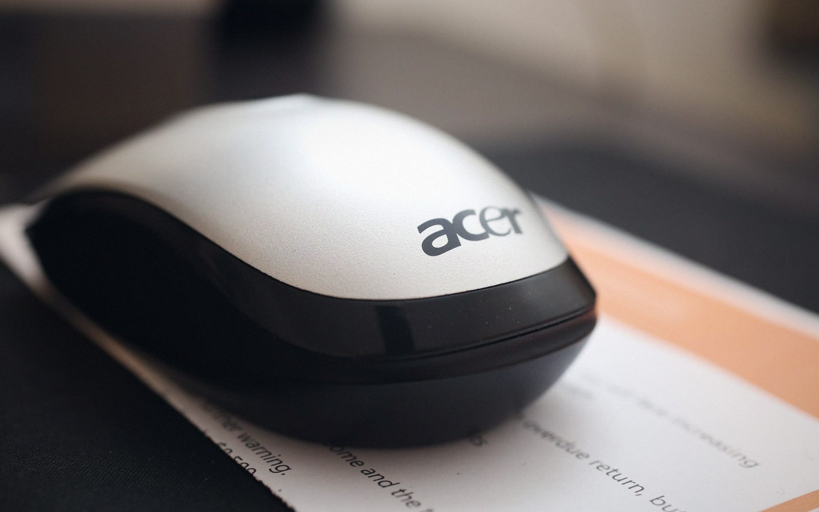 Close-up of a silver and black Acer computer mouse resting on paper documents