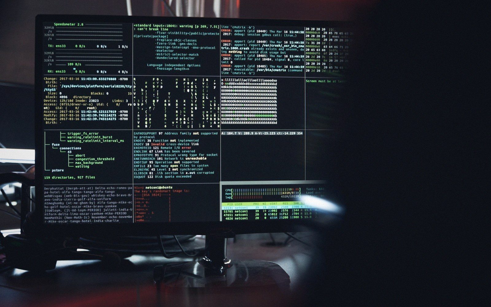 Computer monitor displaying multiple terminal windows with code, logs, and system data