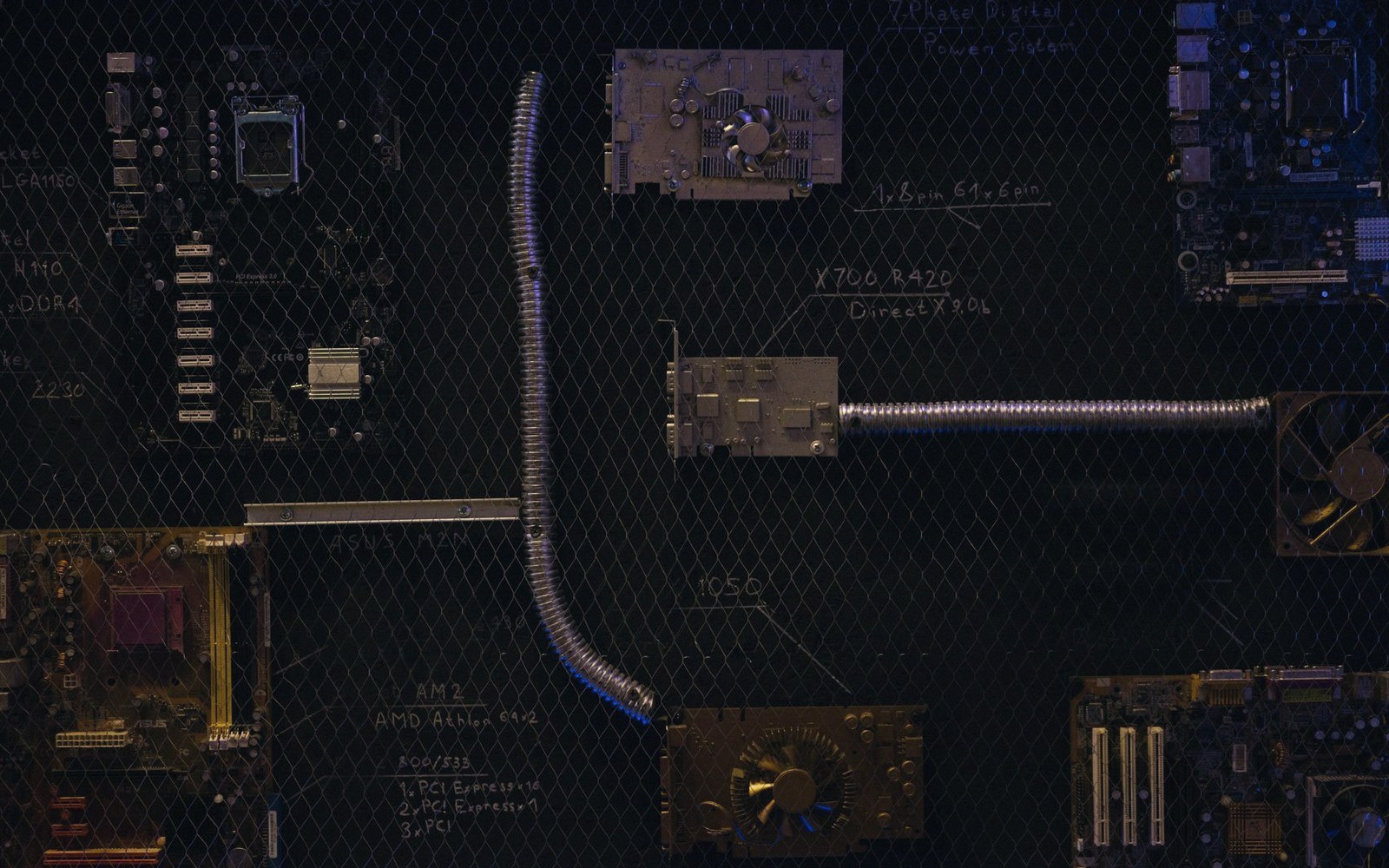 Computer motherboards and components layered behind a wire mesh with handwritten labels